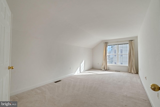 additional living space featuring lofted ceiling and light carpet