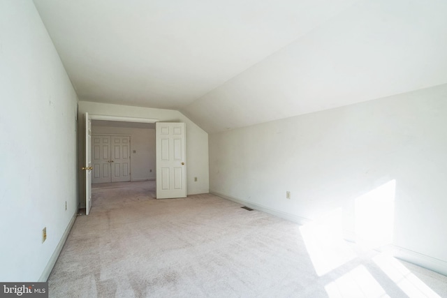 bonus room with light carpet and vaulted ceiling