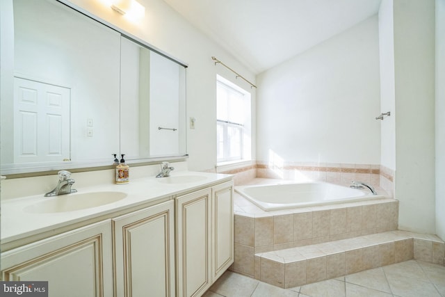 bathroom with a relaxing tiled tub, vaulted ceiling, vanity, and tile patterned flooring