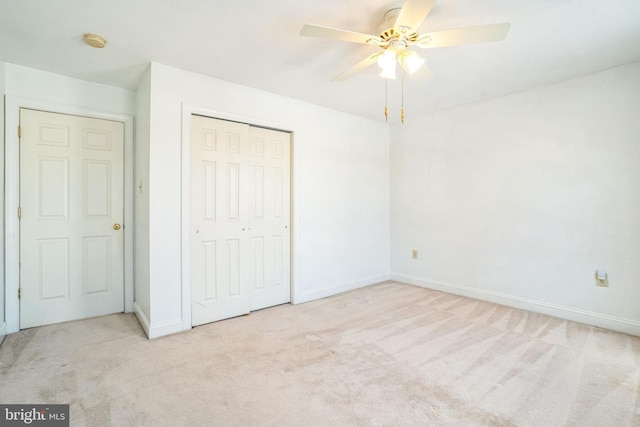 unfurnished bedroom with ceiling fan, a closet, and light carpet