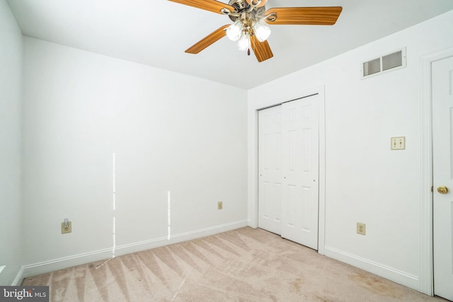 unfurnished bedroom featuring light carpet, ceiling fan, and a closet