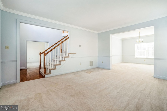 spare room with a notable chandelier, ornamental molding, and carpet flooring