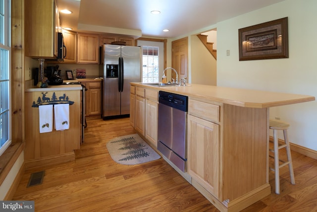 kitchen featuring sink, appliances with stainless steel finishes, light hardwood / wood-style flooring, and a kitchen island with sink