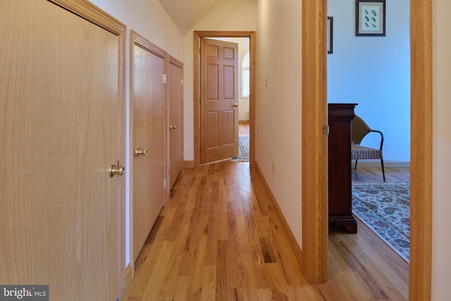 hall with light hardwood / wood-style flooring and lofted ceiling