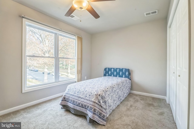 bedroom with ceiling fan, a closet, and light colored carpet