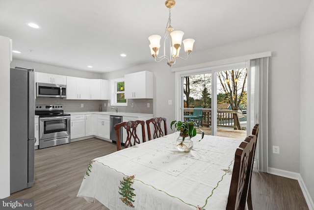 dining space with sink, dark hardwood / wood-style flooring, and a notable chandelier