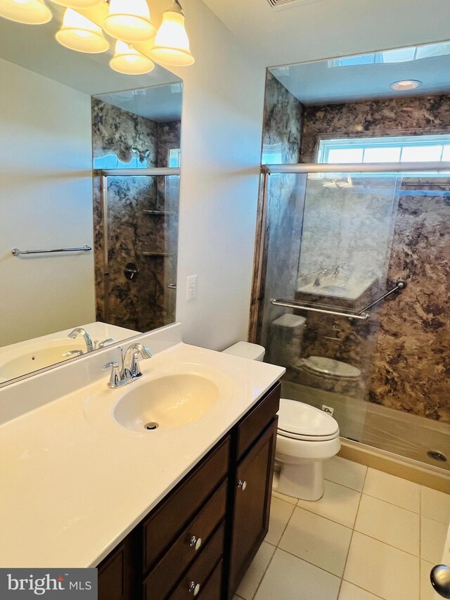 bathroom featuring toilet, vanity, tile patterned floors, and an enclosed shower