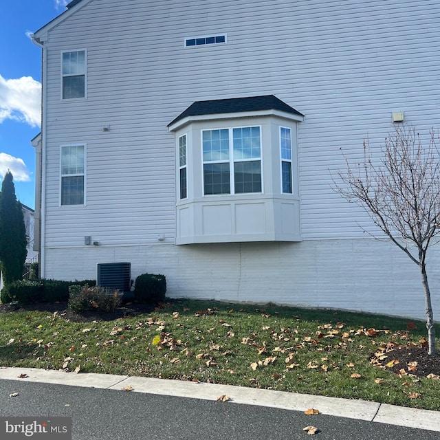 view of side of home with central AC unit and a lawn