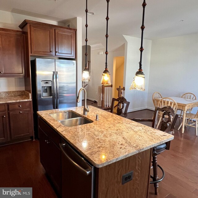 kitchen with sink, hanging light fixtures, dark hardwood / wood-style flooring, a kitchen island with sink, and appliances with stainless steel finishes