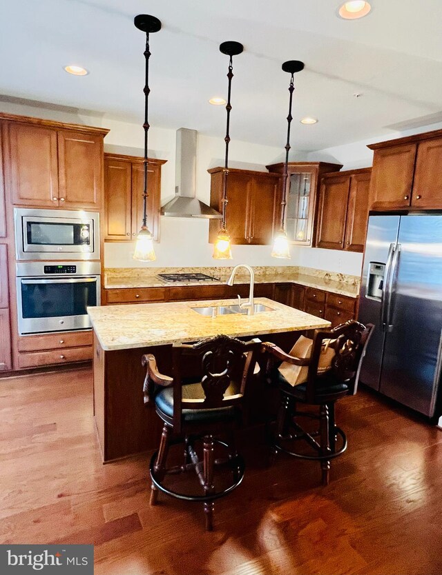 kitchen with pendant lighting, wall chimney range hood, and appliances with stainless steel finishes