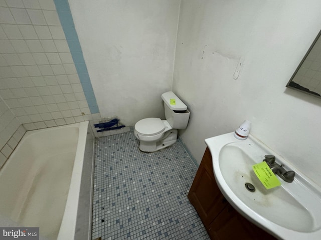 bathroom with vanity, tile patterned floors, toilet, and a washtub