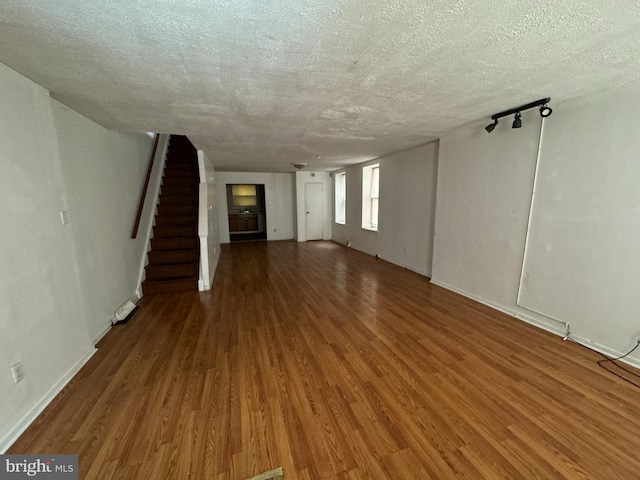 unfurnished living room with a textured ceiling and dark hardwood / wood-style flooring