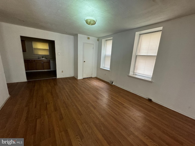 unfurnished bedroom with a textured ceiling, sink, and dark hardwood / wood-style flooring