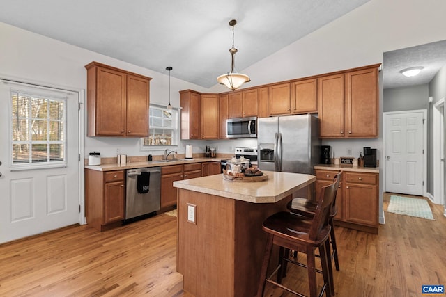 kitchen with pendant lighting, vaulted ceiling, light hardwood / wood-style flooring, and stainless steel appliances