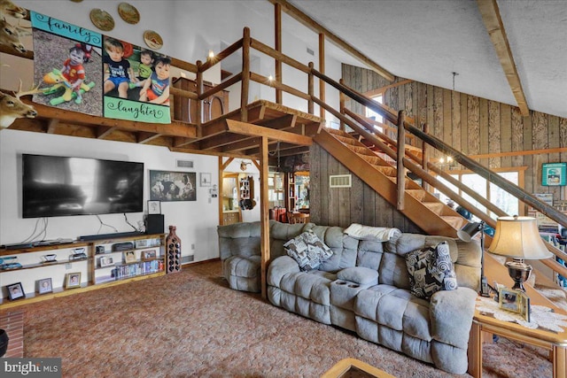 living room with a textured ceiling, vaulted ceiling with beams, carpet floors, and wooden walls