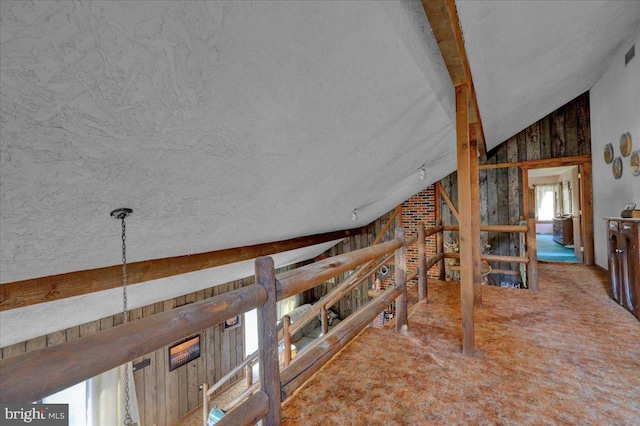 hallway with vaulted ceiling with beams, wood walls, carpet floors, and a textured ceiling