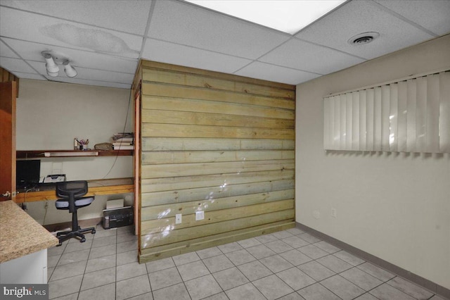 interior space with light tile patterned flooring, a paneled ceiling, and built in desk