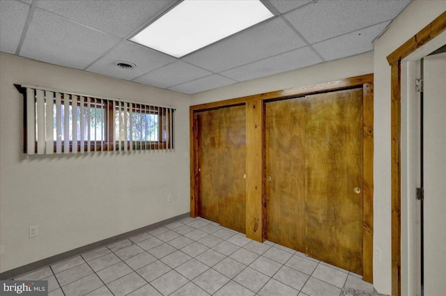 unfurnished bedroom featuring a paneled ceiling and light tile patterned floors