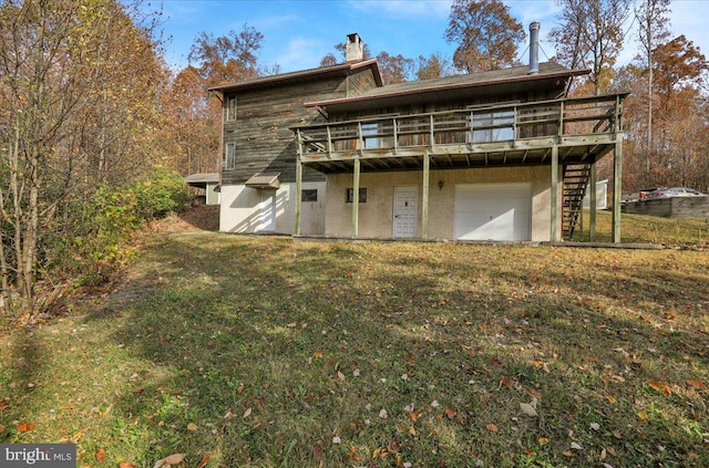 rear view of house with a wooden deck, a garage, and a lawn