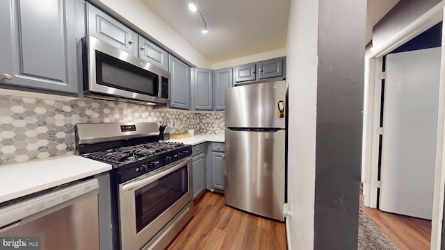 kitchen featuring gray cabinets, backsplash, hardwood / wood-style floors, and stainless steel appliances