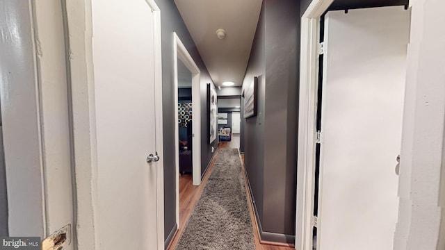 hallway featuring dark colored carpet