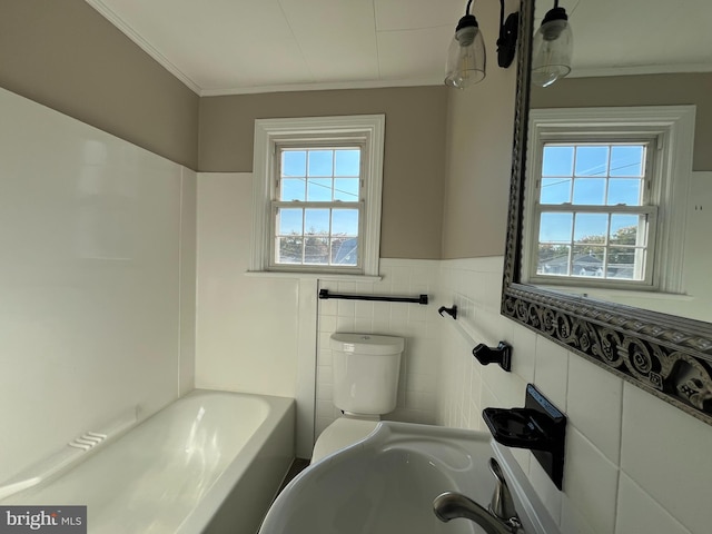 bathroom with toilet, tile walls, a healthy amount of sunlight, and a bath