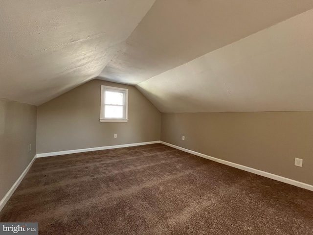 additional living space featuring vaulted ceiling and dark carpet