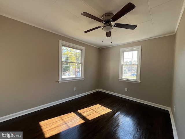 spare room featuring dark wood-type flooring, ceiling fan, a healthy amount of sunlight, and ornamental molding