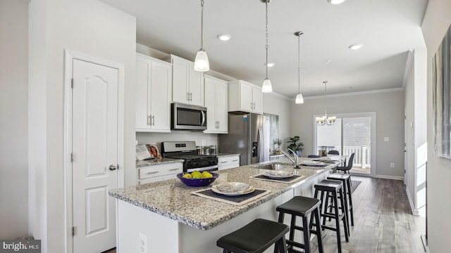 kitchen with white cabinets, stainless steel appliances, a kitchen breakfast bar, and a kitchen island with sink