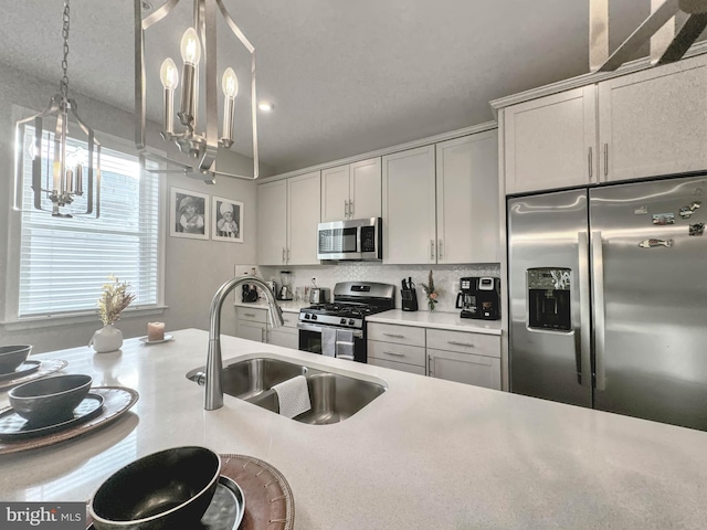 kitchen with white cabinetry, sink, stainless steel appliances, decorative light fixtures, and decorative backsplash