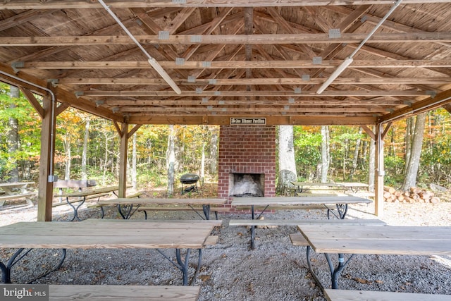 view of patio featuring an outdoor brick fireplace and a gazebo