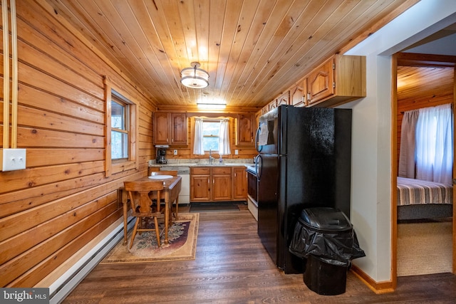 kitchen featuring dishwasher, wood walls, dark wood-type flooring, and black refrigerator