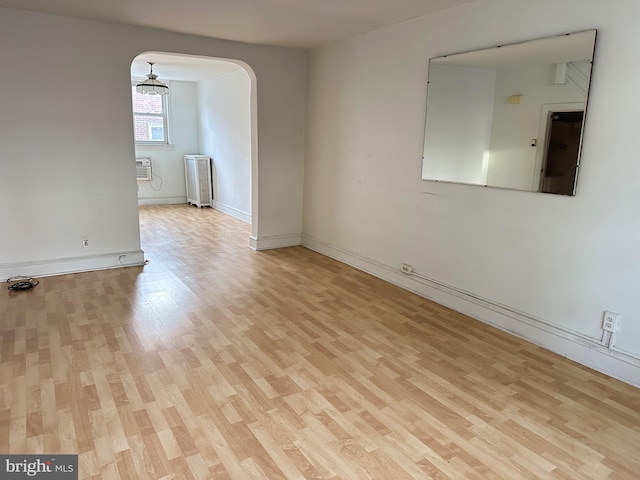 unfurnished room with radiator, a wall mounted AC, and light wood-type flooring