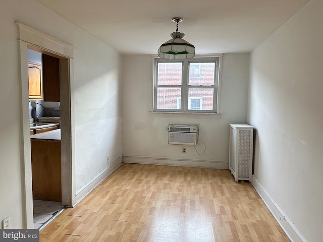 spare room with light hardwood / wood-style flooring, radiator heating unit, and an AC wall unit