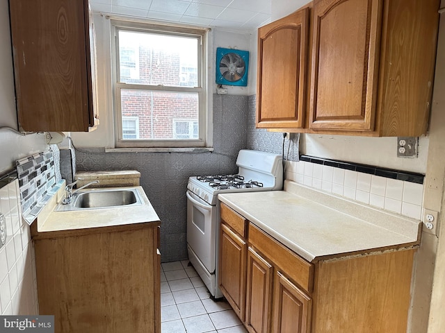 kitchen with tile walls, sink, white gas stove, and light tile patterned floors