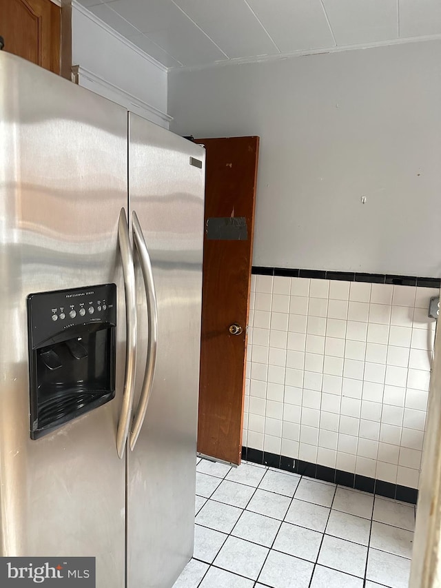 kitchen with light tile patterned flooring, tile walls, and stainless steel fridge with ice dispenser