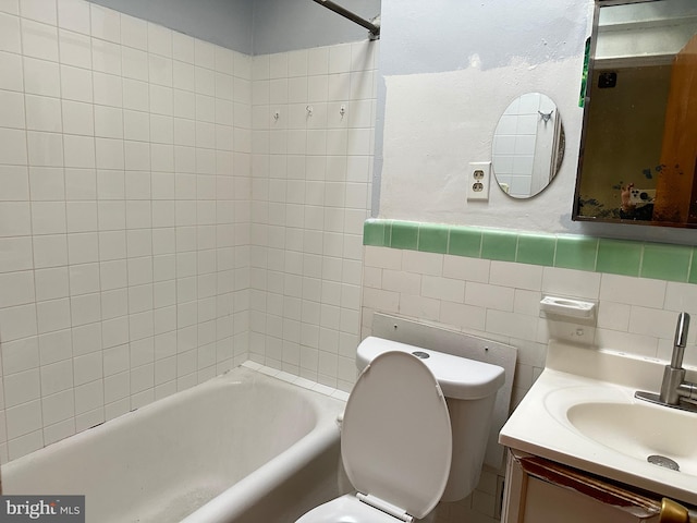 full bathroom with tile walls, vanity, tiled shower / bath, and toilet