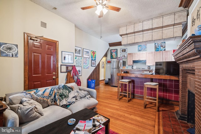 living room with hardwood / wood-style floors, a textured ceiling, ceiling fan, and a fireplace