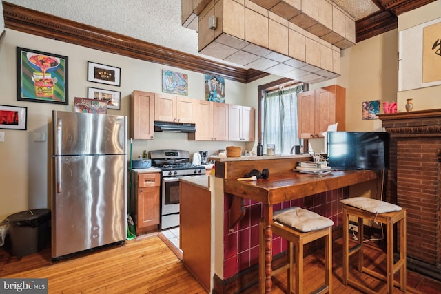 kitchen with a textured ceiling, appliances with stainless steel finishes, light hardwood / wood-style floors, and crown molding