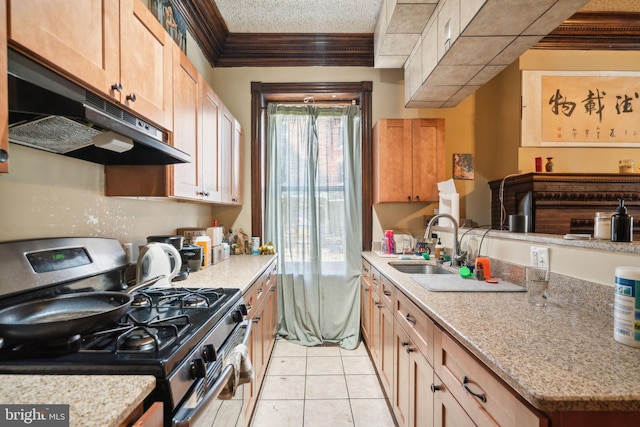 kitchen featuring light stone counters, light tile patterned flooring, ornamental molding, stainless steel gas range, and sink