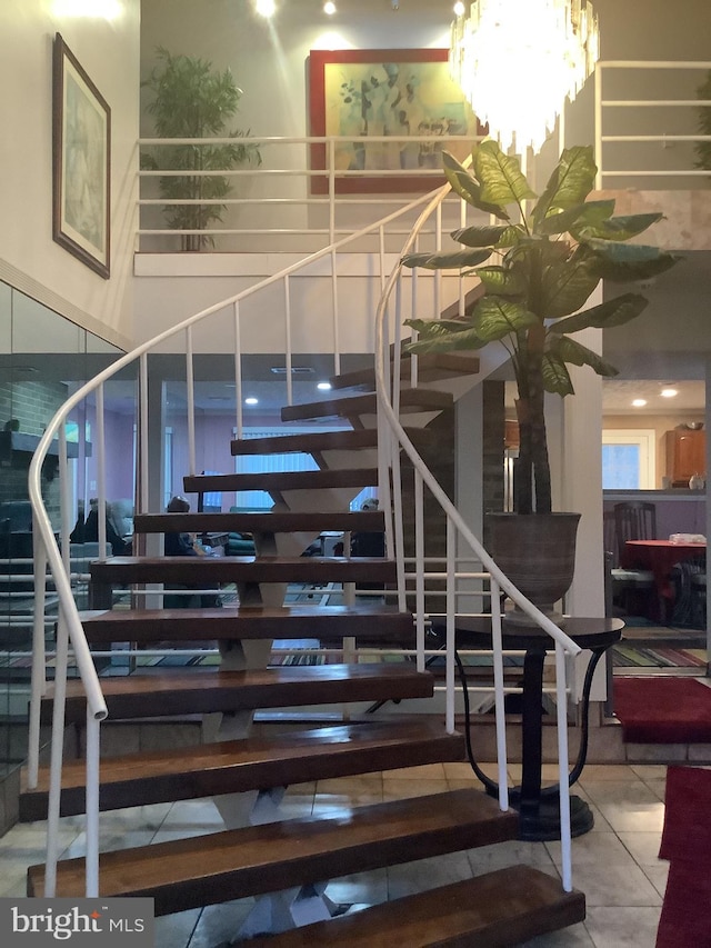 stairs with tile patterned floors and an inviting chandelier