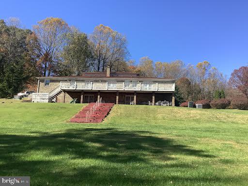 rear view of house with a lawn and a wooden deck