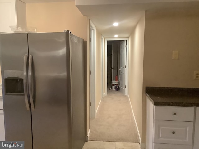 kitchen with white cabinetry, light carpet, and stainless steel fridge