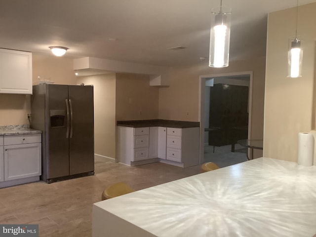 kitchen with white cabinets, light hardwood / wood-style flooring, decorative light fixtures, and stainless steel fridge with ice dispenser