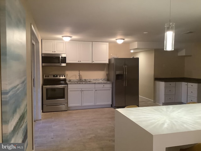 kitchen featuring hanging light fixtures, white cabinetry, sink, and appliances with stainless steel finishes