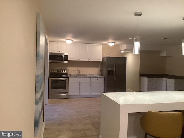 kitchen with white cabinetry, sink, pendant lighting, and appliances with stainless steel finishes