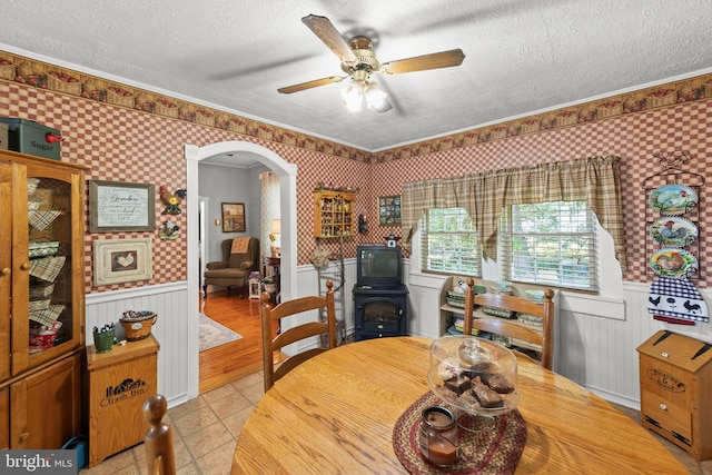 tiled dining space with ceiling fan, crown molding, and a textured ceiling