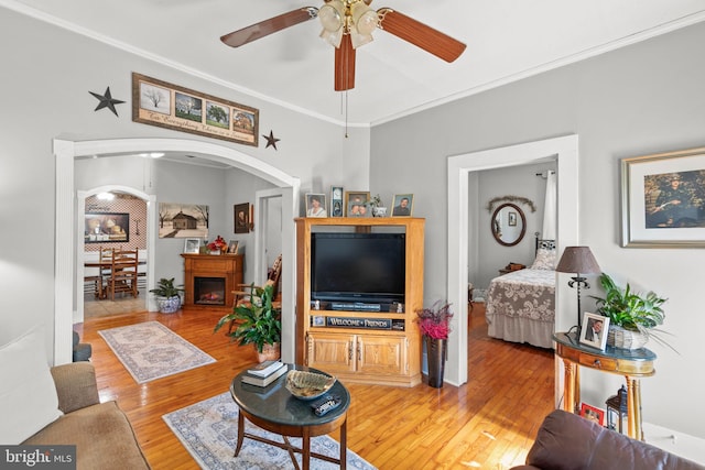 living room with light hardwood / wood-style floors, crown molding, and ceiling fan