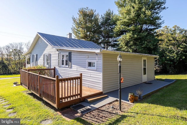 rear view of property featuring a wooden deck and a lawn