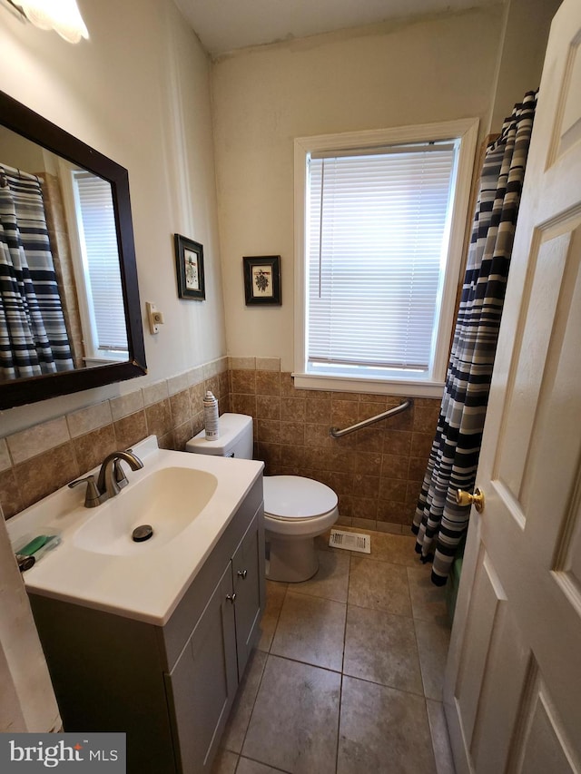 bathroom with a shower with shower curtain, toilet, tile walls, vanity, and tile patterned flooring